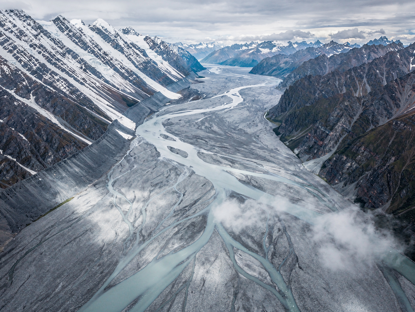 Braided alpine river flowing through mountain ranges in New Zealand